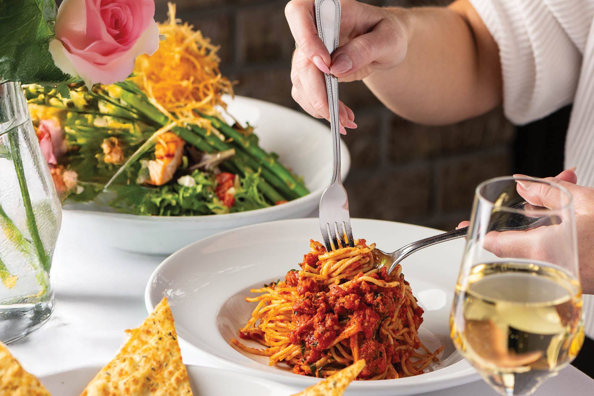 A woman eating Spaghetti Pomodoro and a side salad